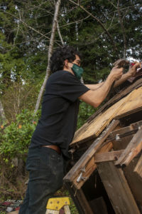 Daniel Chaidez stands on a ladder to remove nails from the roof of the yurt.
