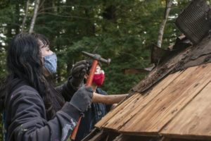 Abbie Ramirez uses a hammer to remove shingles from the yurt roof.