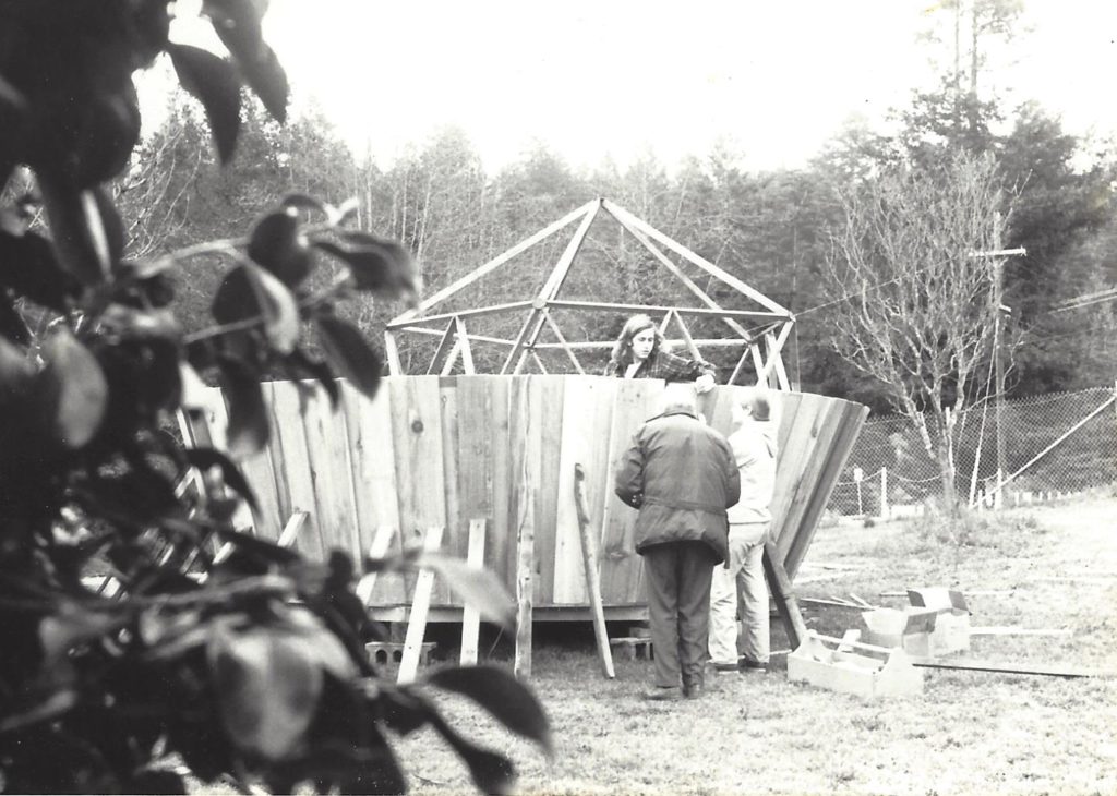 A black and white photo of people constructing the walls of the yurt.