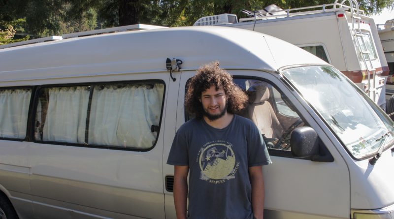 Ryan Kelly, a student at Cal Poly Humboldt, stands next to the van that he lives in.