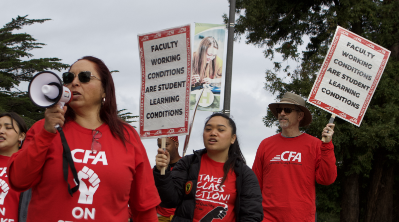 Faculty and students cross the street in red shirts holding signs. The professor in the front holds a megaphone. Student and CFA member behind her hold signs that read "faculty working conditions are student learning conditions."