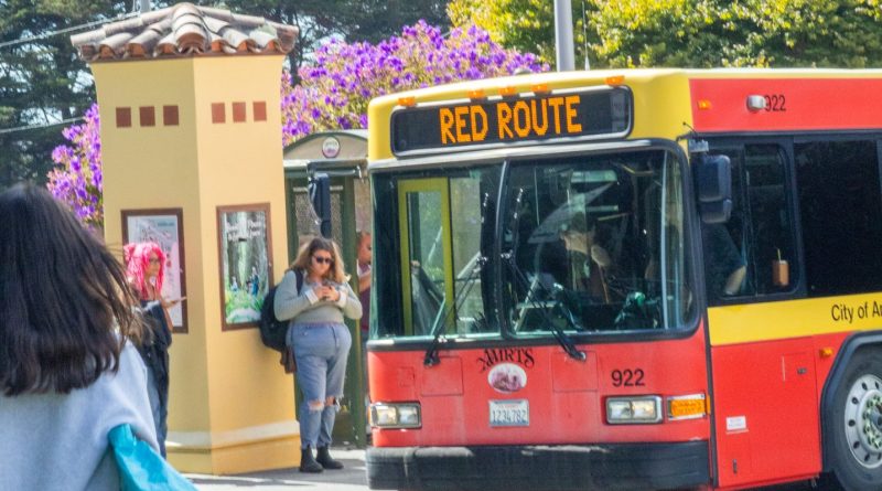 Photo of bus red route and students standing nearby.